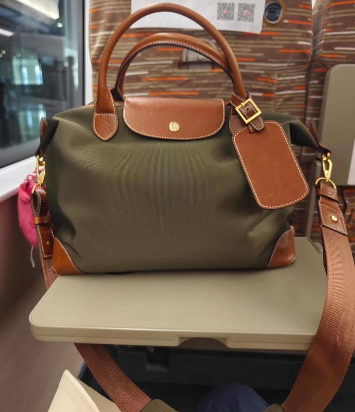 Olive green nylon tote bag with brown leather handles and accents on a train tray table