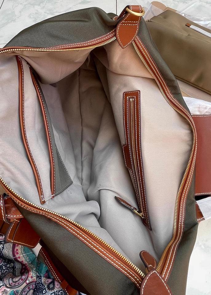Interior view of a large waterproof nylon tote bag with brown cowhide trim, zippered compartments, and spacious main pocket.