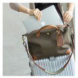 Waterproof nylon and cowhide tote bag with leather trim, holding a laptop, on a suitcase