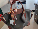 Waterproof nylon and cowhide tote bag with brown leather handles and orange patterned scarf accent.