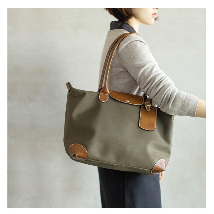 Woman carrying olive green waterproof nylon and cowhide tote bag with brown leather accents