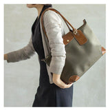 Woman carrying olive green nylon tote bag with brown leather handles and accents