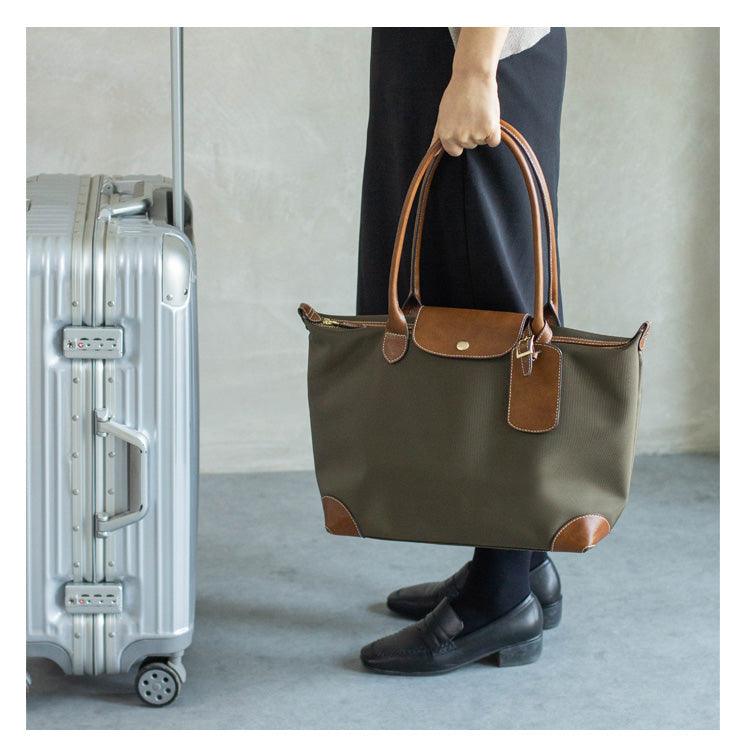 Handcrafted waterproof nylon and cowhide tote bag for travel and work, shown with suitcase