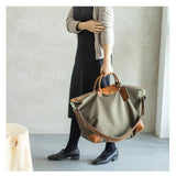 Woman holding large olive waterproof nylon and cowhide weekend tote bag with leather trim