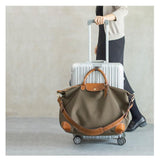 Waterproof nylon and cowhide tote bag with brown leather accents on a silver rolling suitcase