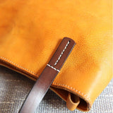 Close-up of tan full grain leather tote bag with brown leather handle and contrast stitching