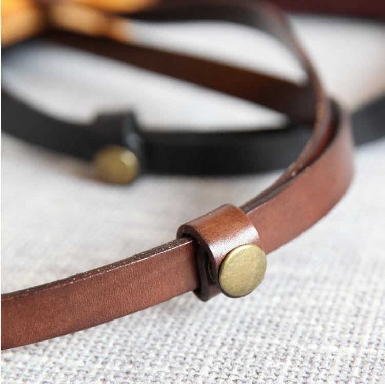 Close-up of brown and black genuine leather handbag straps with brass rivets