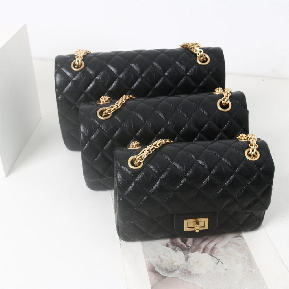 Woman in white shirt carrying black quilted leather shoulder bag with gold chain strap