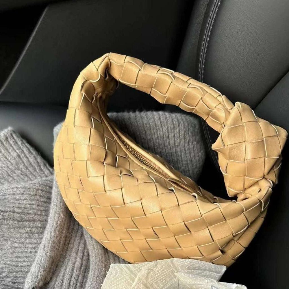 Tan woven leather handbag with a knotted handle on a car seat, luxury designer bag style