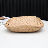 Beige woven leather clutch bag with a soft, flat design on a white table.