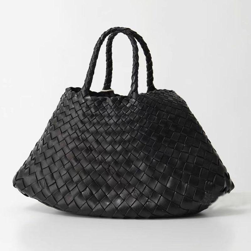 Woman holding black woven leather hobo bag with dual handles, stylish and trapezoidal shape black