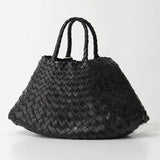 Woman holding black woven leather hobo bag with dual handles, stylish and trapezoidal shape black