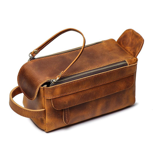 Brown genuine leather toiletry bag with zipper, handle, and front pocket on white background.