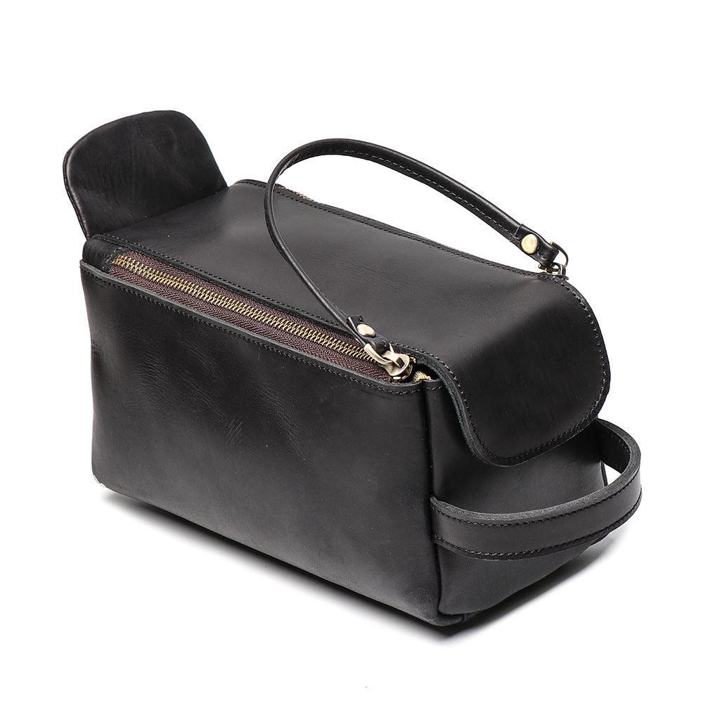 Black genuine leather toiletry bag with handle and gold zipper on white background