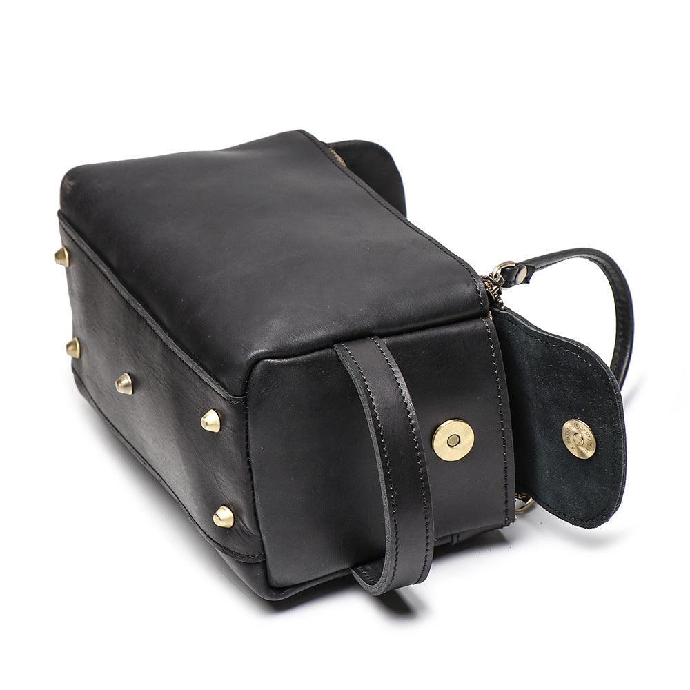 Black genuine leather handbag with gold hardware, top handle, and studded bottom