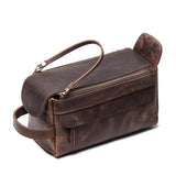 Brown genuine leather toiletry bag with top zipper, side handle, and front pocket on white background