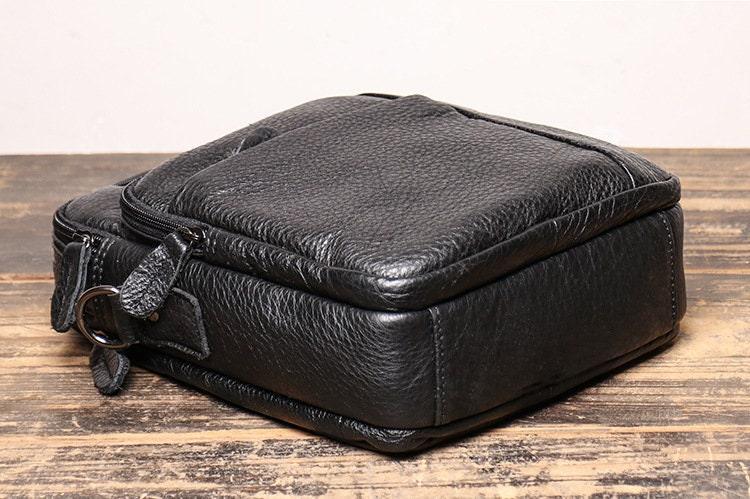 Black leather men's crossbody shoulder bag with textured finish on wooden surface