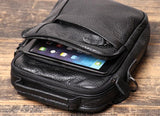 Black leather men's crossbody shoulder bag with tablet in zippered front pocket on wooden surface