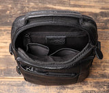 Open black leather men's crossbody shoulder bag with multiple interior compartments on wood surface