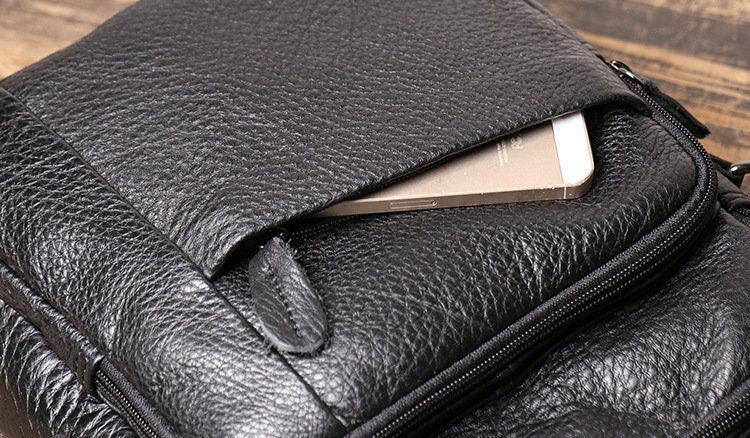 Black leather men's crossbody shoulder bag with phone pocket on wooden surface