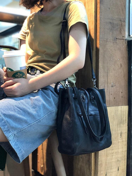 Woman holding coffee and wearing a large black leather shoulder bag, casual outfit