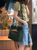 Woman carrying a large green leather shoulder bag with zipper detail, casual street style
