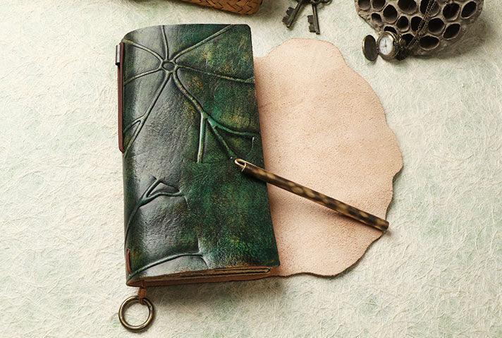 Green embossed leather journal with keyring, tortoiseshell pen, and textured background