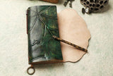 Green embossed leather journal with keyring, tortoiseshell pen, and textured background