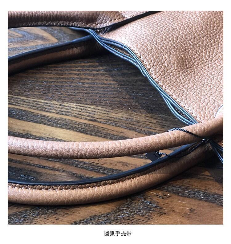 Textured full grain leather tote bag with round handles on a wooden surface