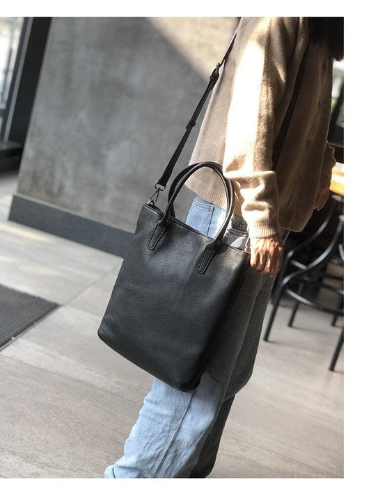 Woman carrying large black full grain leather tote bag with shoulder strap