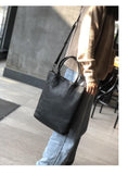 Woman carrying large black full grain leather tote bag with shoulder strap