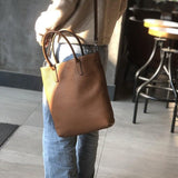 Woman carrying a brown full grain leather tote crossbody bag indoors