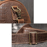 Close-up of brown crocodile-embossed full-grain leather duffle bag with brass hardware