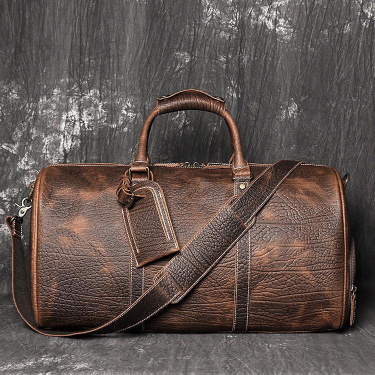 Full grain brown leather duffle bag with shoulder strap and luggage tag, cowhide texture