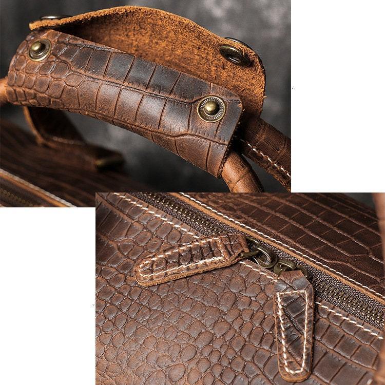 Close-up of brown full grain leather travel duffle bag with textured cowhide pattern, sturdy handles, and zipper detail.