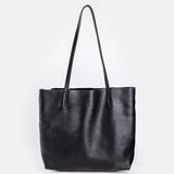 Large black full-grain leather tote bag with long handles on white background