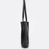 Side view of large black full-grain leather tote bag with long handles
