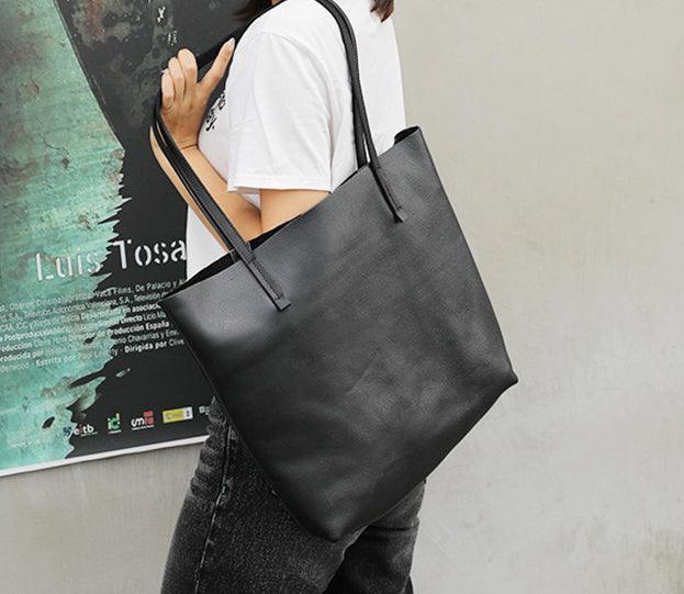 Woman carrying large black full grain leather tote bag with double handles