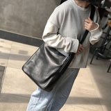 Woman wearing a black full grain leather shoulder bag with wide strap, casual outfit