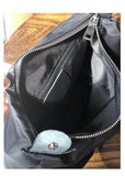 Interior of a full grain leather shoulder bag with zipper pocket and snap button, on wooden table