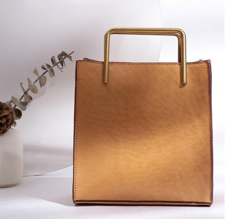 Tan genuine cowhide leather shoulder bag with gold square handle on white background