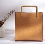 Tan genuine cowhide leather shoulder bag with gold square handle on white background