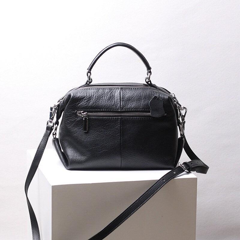 Black genuine leather handbag with top handle, shoulder strap, and front zipper pocket
