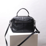 Black genuine leather handbag with top handle, shoulder strap, and front zipper pocket
