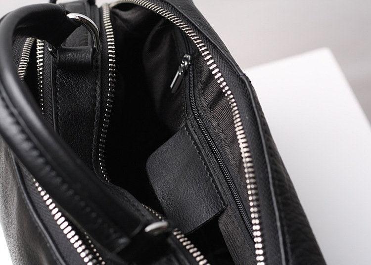 Open black genuine leather handbag showing interior pockets and silver zipper detail