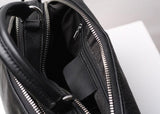 Open black genuine leather handbag showing interior pockets and silver zipper detail