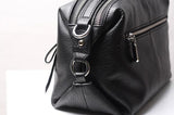 Black genuine leather handbag with zip closure and silver hardware on a white surface