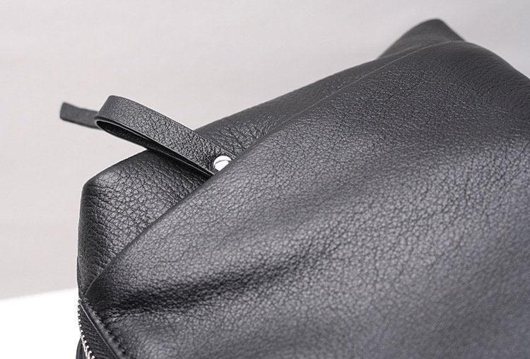 Close-up of a black genuine leather handbag with grain texture and zipper detail