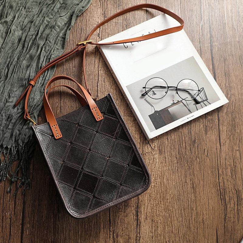 Handcrafted cowhide leather crossbody bag with brown handles on wood background