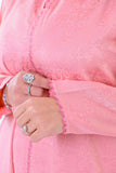 Close-up of hands wearing silver rings, holding pink embroidered jacquard kaftan sleeve